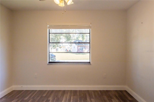 empty room featuring a ceiling fan, dark wood finished floors, and baseboards