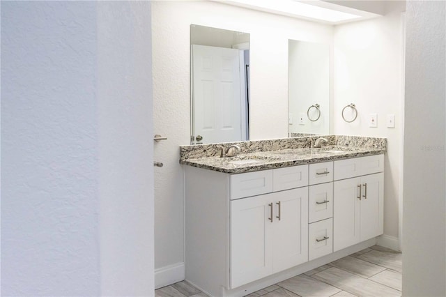 bathroom featuring double vanity, a sink, and baseboards