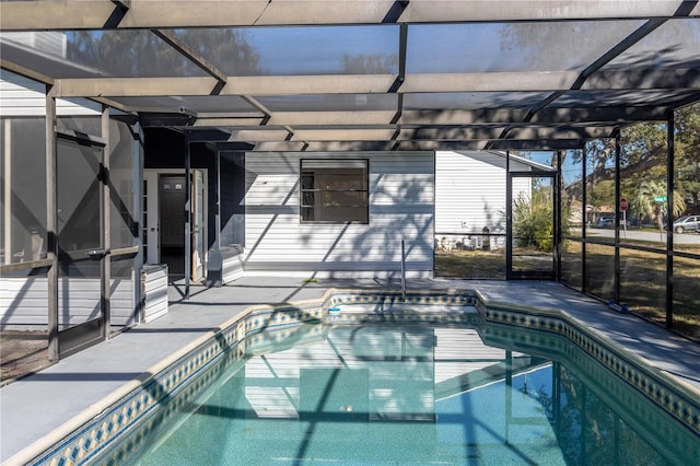 outdoor pool featuring glass enclosure and a patio