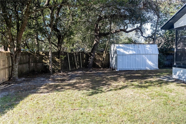 view of yard featuring a storage shed, a fenced backyard, and an outbuilding