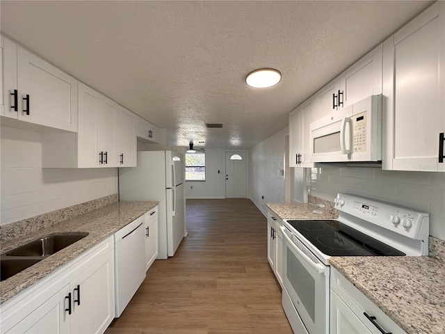 kitchen with light wood-type flooring, white appliances, white cabinets, and backsplash