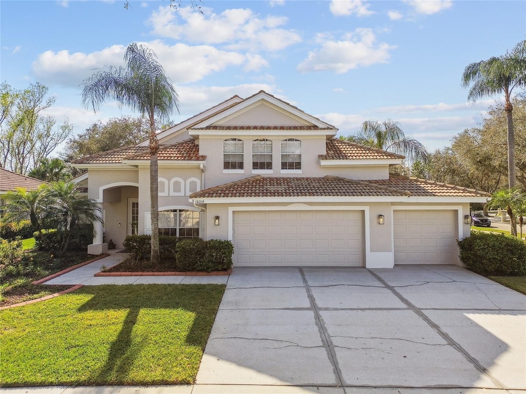 mediterranean / spanish-style house with concrete driveway, a tile roof, stucco siding, and an attached garage