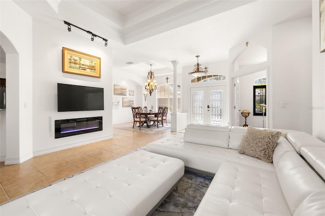 tiled living room featuring ornamental molding, french doors, a chandelier, and track lighting