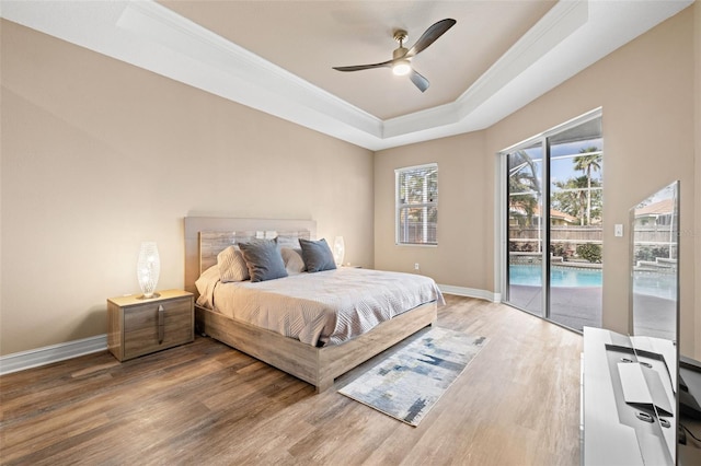 bedroom with hardwood / wood-style flooring, ceiling fan, a raised ceiling, access to exterior, and ornamental molding