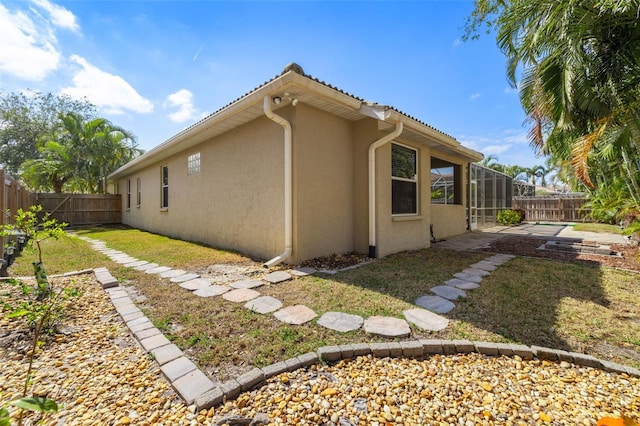 view of side of property featuring a lawn and glass enclosure