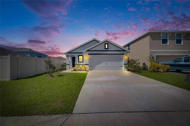 view of front facade with stucco siding, an attached garage, fence, driveway, and a front lawn