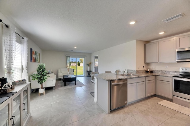 kitchen with open floor plan, visible vents, stainless steel appliances, and gray cabinetry