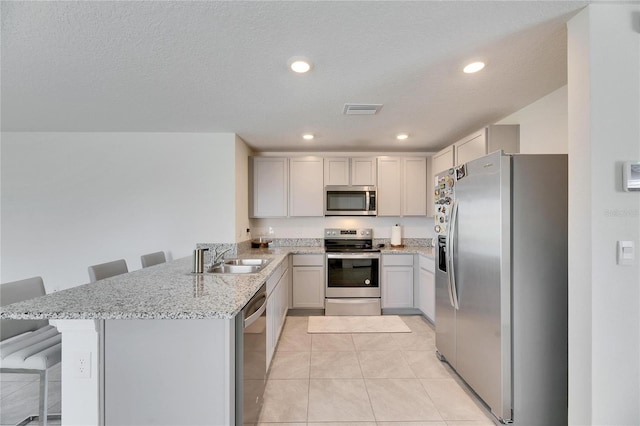 kitchen with visible vents, a breakfast bar area, appliances with stainless steel finishes, a peninsula, and a sink