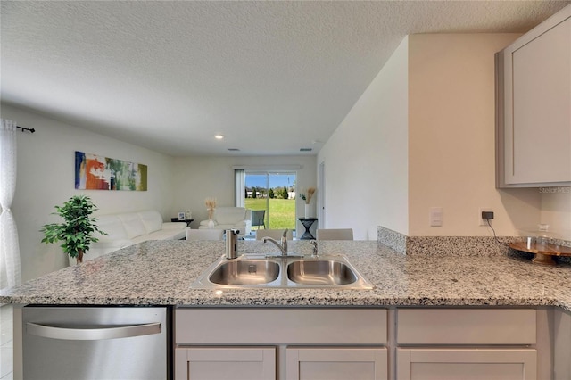 kitchen with open floor plan, a sink, a textured ceiling, dishwasher, and a peninsula