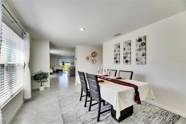 dining area featuring plenty of natural light, visible vents, a textured ceiling, and light tile patterned flooring