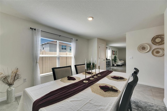 dining room featuring tile patterned flooring, baseboards, and a textured ceiling