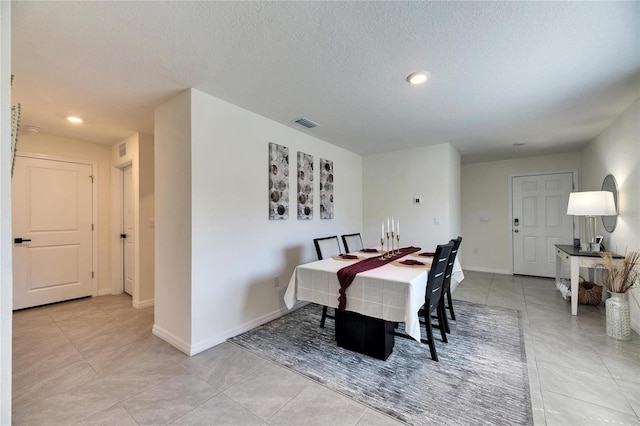 dining space with light tile patterned floors, baseboards, visible vents, and a textured ceiling