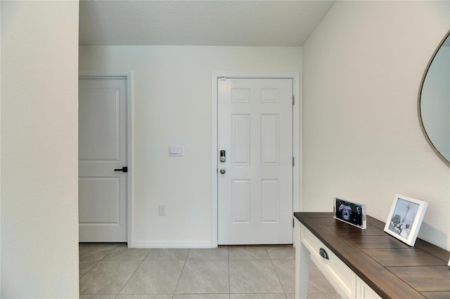 foyer entrance with light tile patterned floors and baseboards