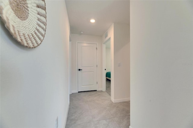 hallway with light tile patterned floors, recessed lighting, visible vents, and baseboards