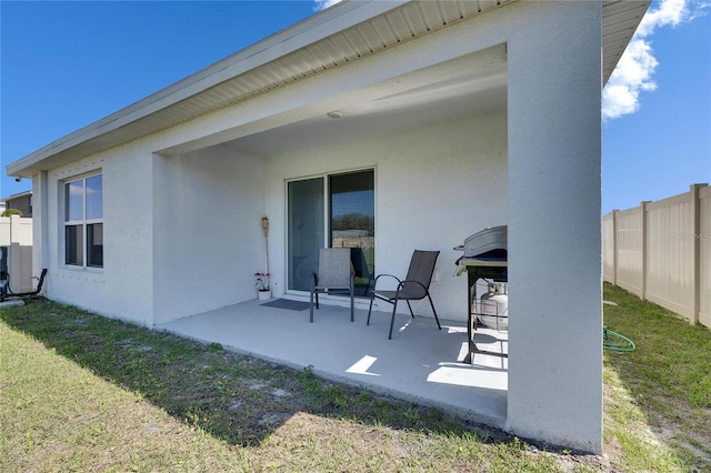 rear view of property with a lawn, a patio area, fence, and stucco siding