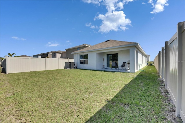 rear view of property with a fenced backyard, a yard, central AC unit, and stucco siding