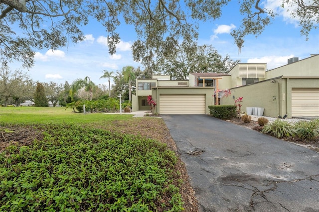 view of front facade with a front yard, aphalt driveway, and stucco siding