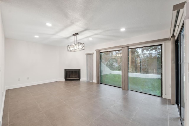 unfurnished living room with a textured ceiling, a fireplace, baseboards, and recessed lighting