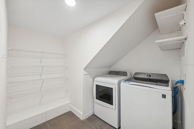 washroom featuring laundry area, baseboards, dark tile patterned flooring, and washing machine and clothes dryer