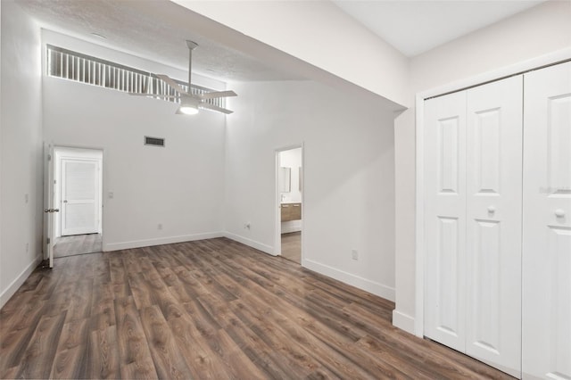 interior space with dark wood-style floors, visible vents, high vaulted ceiling, and baseboards