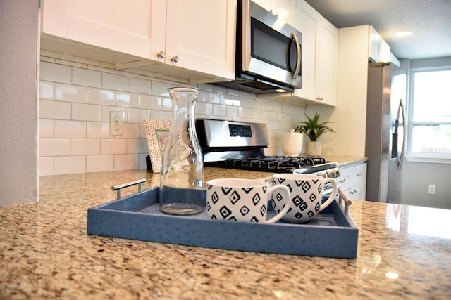 kitchen with appliances with stainless steel finishes, white cabinetry, and light stone countertops