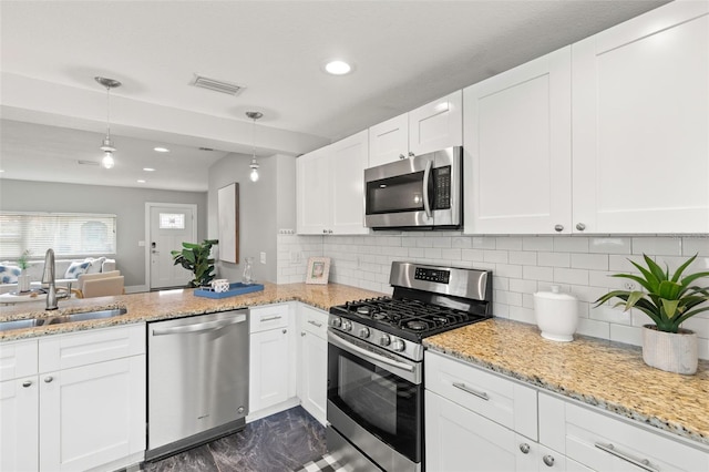 kitchen with visible vents, decorative light fixtures, stainless steel appliances, white cabinetry, and a sink