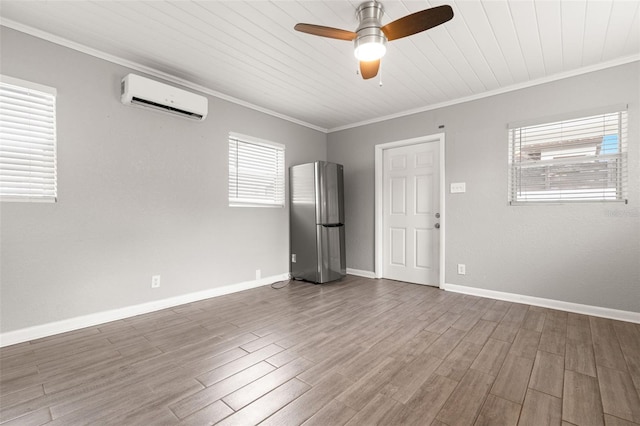 empty room with ornamental molding, wood finished floors, baseboards, and a wall mounted AC