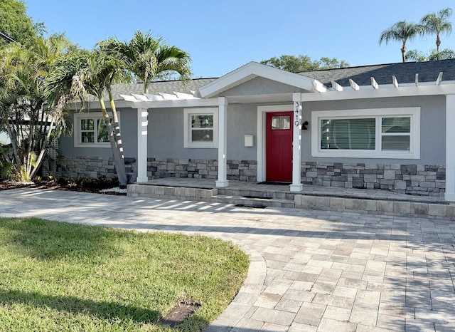 3419 W Empedrado St, Tampa, FL 33629 - view of front facade with stone siding, stucco siding, covered porch, and a front lawn