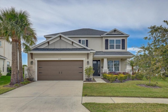 craftsman-style house with a front yard, stucco siding, driveway, and a shingled roof