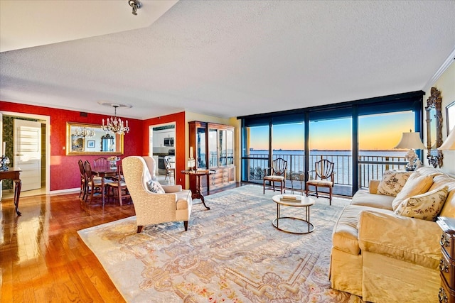 living room featuring wood finished floors, a water view, plenty of natural light, and an inviting chandelier