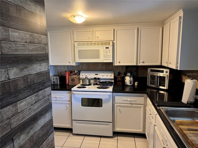 kitchen featuring dark countertops, white appliances, white cabinets, and light tile patterned floors