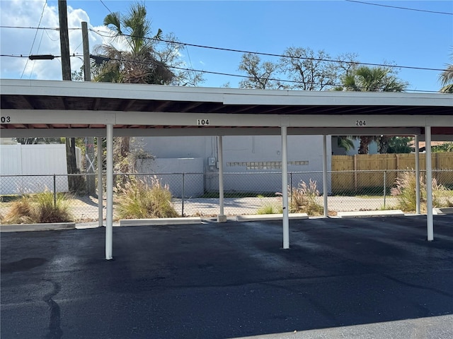 covered parking lot featuring fence