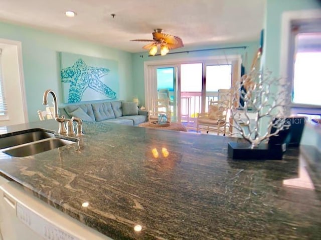 kitchen featuring ceiling fan, sink, and dark stone countertops