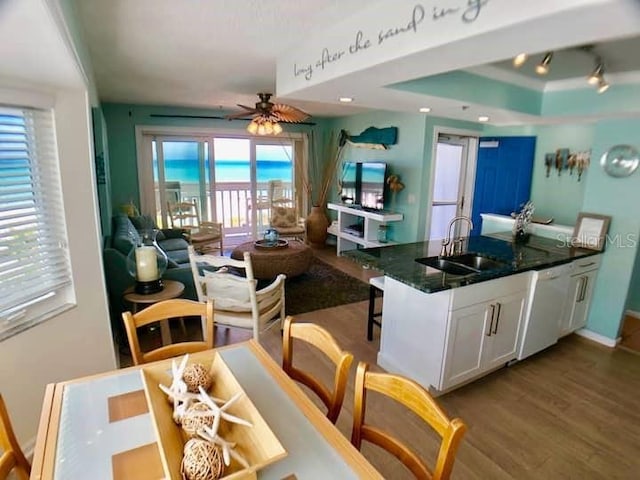 kitchen with white dishwasher, light hardwood / wood-style flooring, white cabinets, ceiling fan, and sink