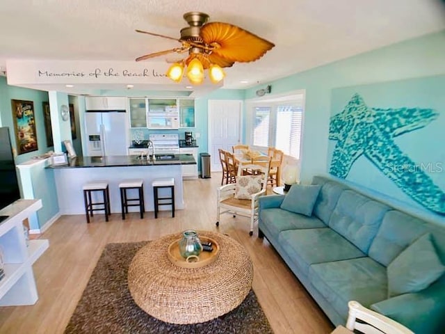 living room featuring light wood-type flooring, sink, and ceiling fan