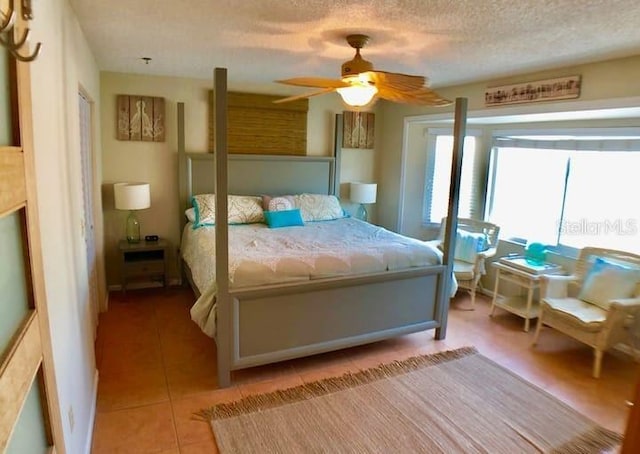 tiled bedroom with ceiling fan and a textured ceiling