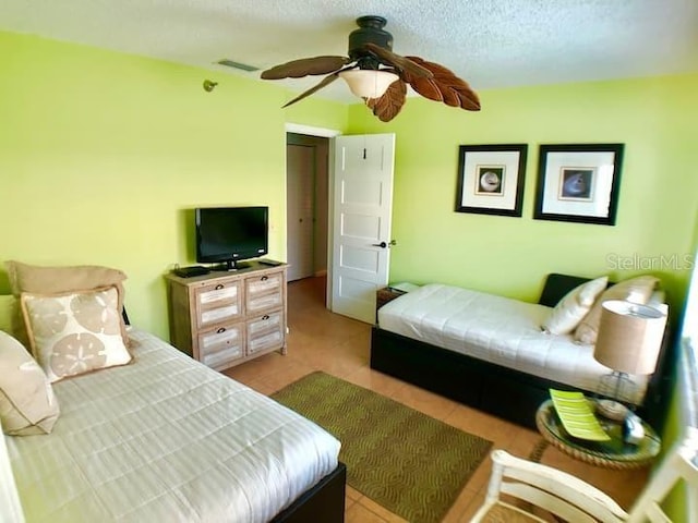 bedroom featuring a textured ceiling, ceiling fan, and light tile patterned floors