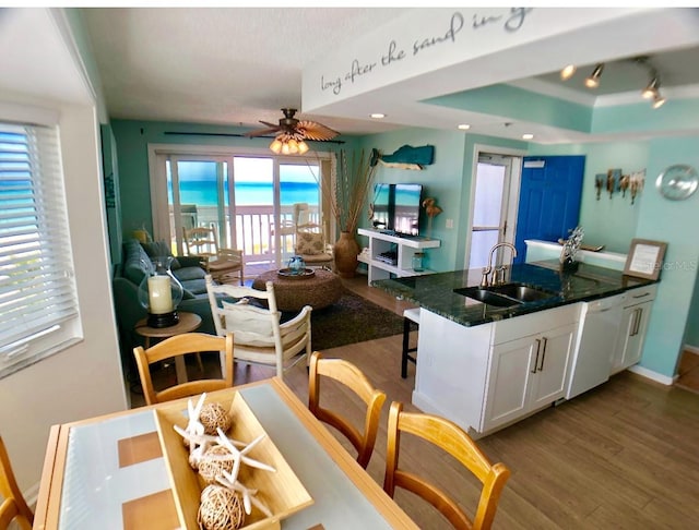 kitchen featuring light hardwood / wood-style flooring, sink, white dishwasher, white cabinetry, and dark stone countertops