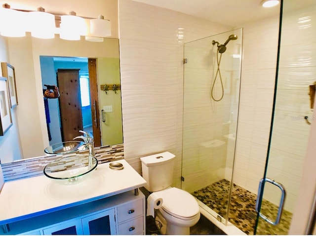 bathroom with vanity, walk in shower, toilet, and tasteful backsplash