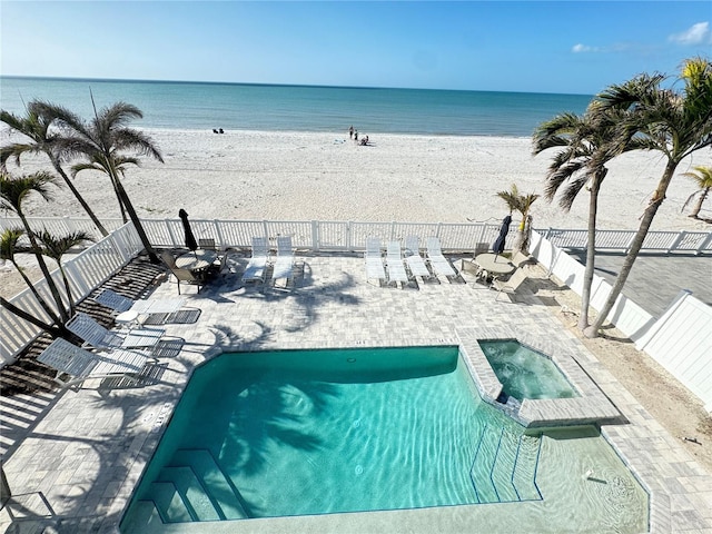 view of swimming pool with a hot tub, a beach view, a water view, and a patio area