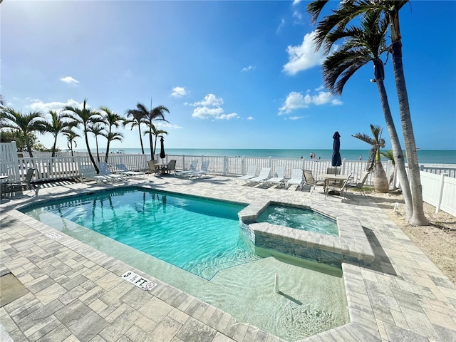 view of swimming pool with a patio, a water view, and a community hot tub