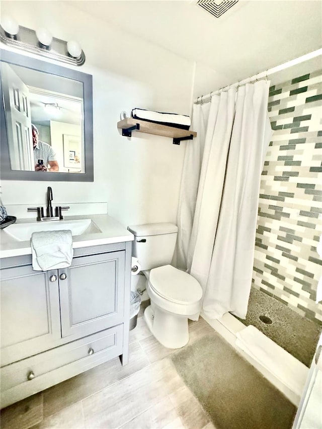 bathroom with toilet, a shower stall, visible vents, and vanity