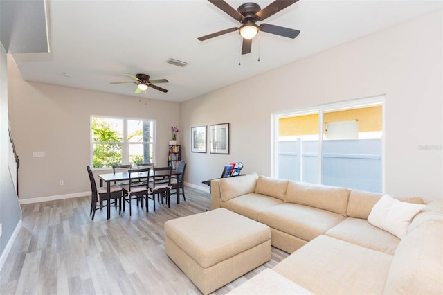 living area featuring visible vents, baseboards, light wood-style flooring, and a ceiling fan