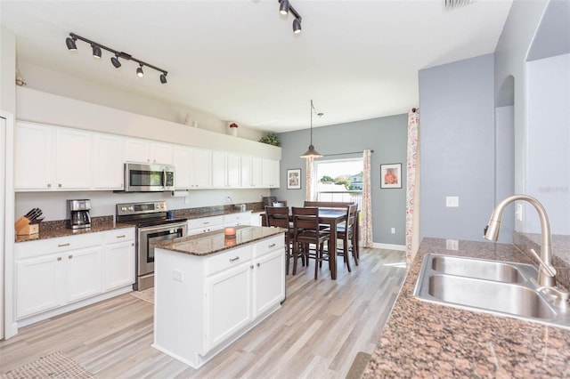 kitchen featuring white cabinets, light wood-style floors, appliances with stainless steel finishes, and a sink