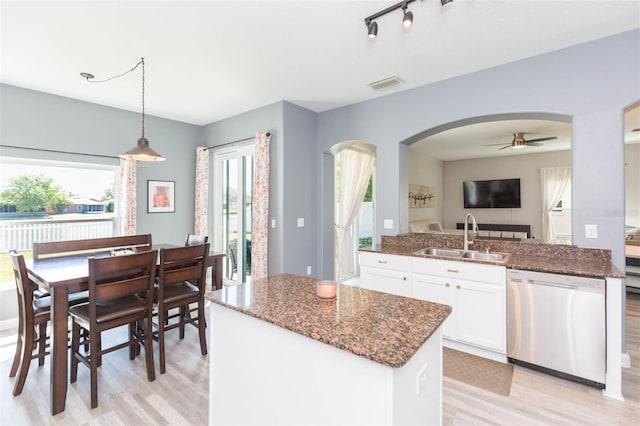 kitchen featuring visible vents, dark stone counters, arched walkways, a sink, and stainless steel dishwasher