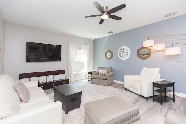 living area featuring a ceiling fan, wood finished floors, visible vents, and baseboards