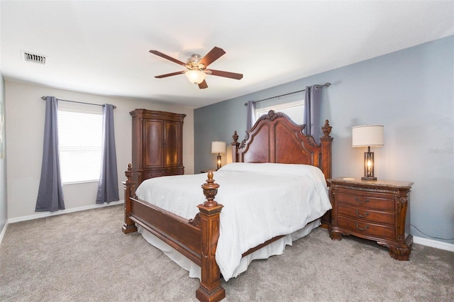 bedroom with visible vents, light colored carpet, baseboards, and ceiling fan