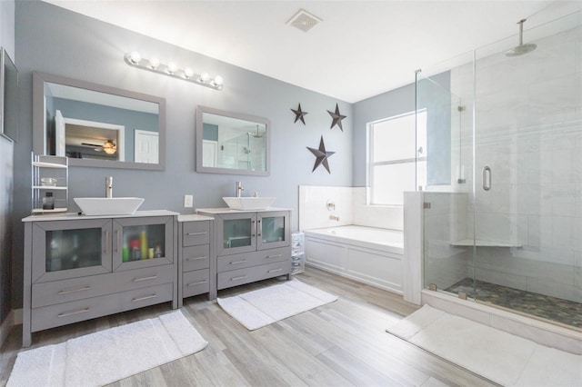 bathroom with a bath, a shower stall, wood finished floors, and a sink