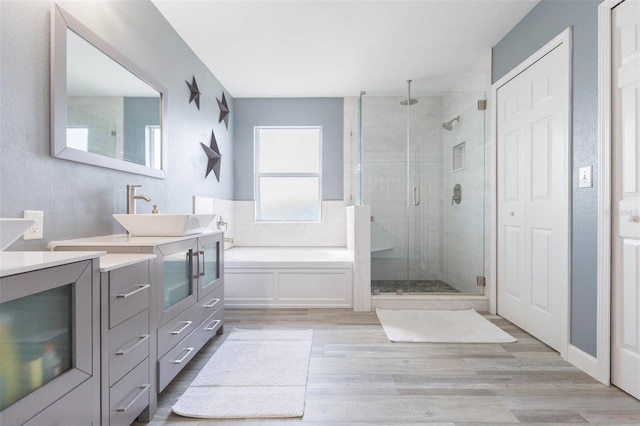 full bath featuring wood finished floors, vanity, a bath, and a shower stall