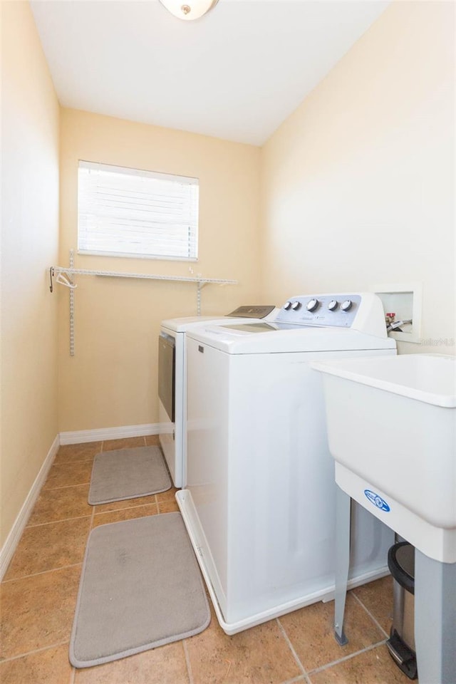 clothes washing area with washer and dryer, laundry area, and baseboards